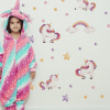 Fetita in camera ei, cu perete lipit cu autocolante de perete unicorni, steluțe, curcubeu, in culori roz pastel